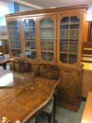 A walnut four door bookcase, extending dining table and four walnut chairs