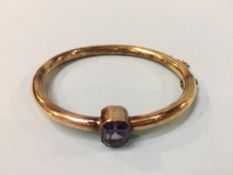 A yellow metal bangle, mounted with an amethyst