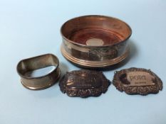 A silver wine coaster, two decanter labels and a napkin ring