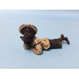 A cold painted bronze of a boy lying on his front, cross legged, stamped Geschutzi 5136, 9cm length
