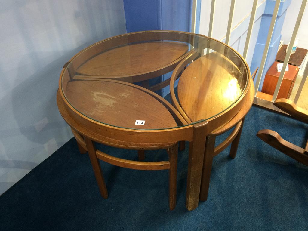 A teak and glass circular coffee table, with three oval small tables