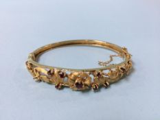 A Victorian 9ct gold (stamped 375), floral bangle set with eight rubies, total weight 15.7g