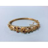 A Victorian 9ct gold (stamped 375), floral bangle set with eight rubies, total weight 15.7g