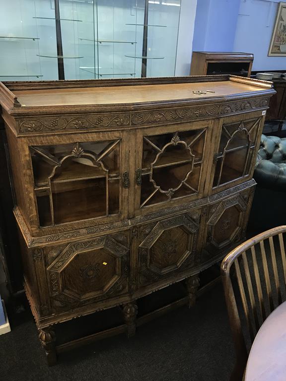An oak Lees heavily carved oak cabinet, with three glazed doors and decorative panelled doors below,
