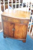 A reproduction mahogany bow front cabinet, with single drawer and two cupboard doors, 70cm wide