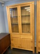 A pale oak two door display cabinet