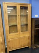 A pale oak two door display cabinet