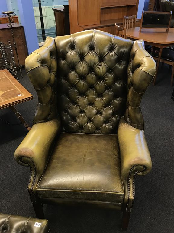 An olive green leather Chesterfield wing armchair