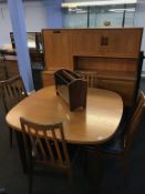 A teak G Plan high back sideboard, table and four chairs with a magazine rack