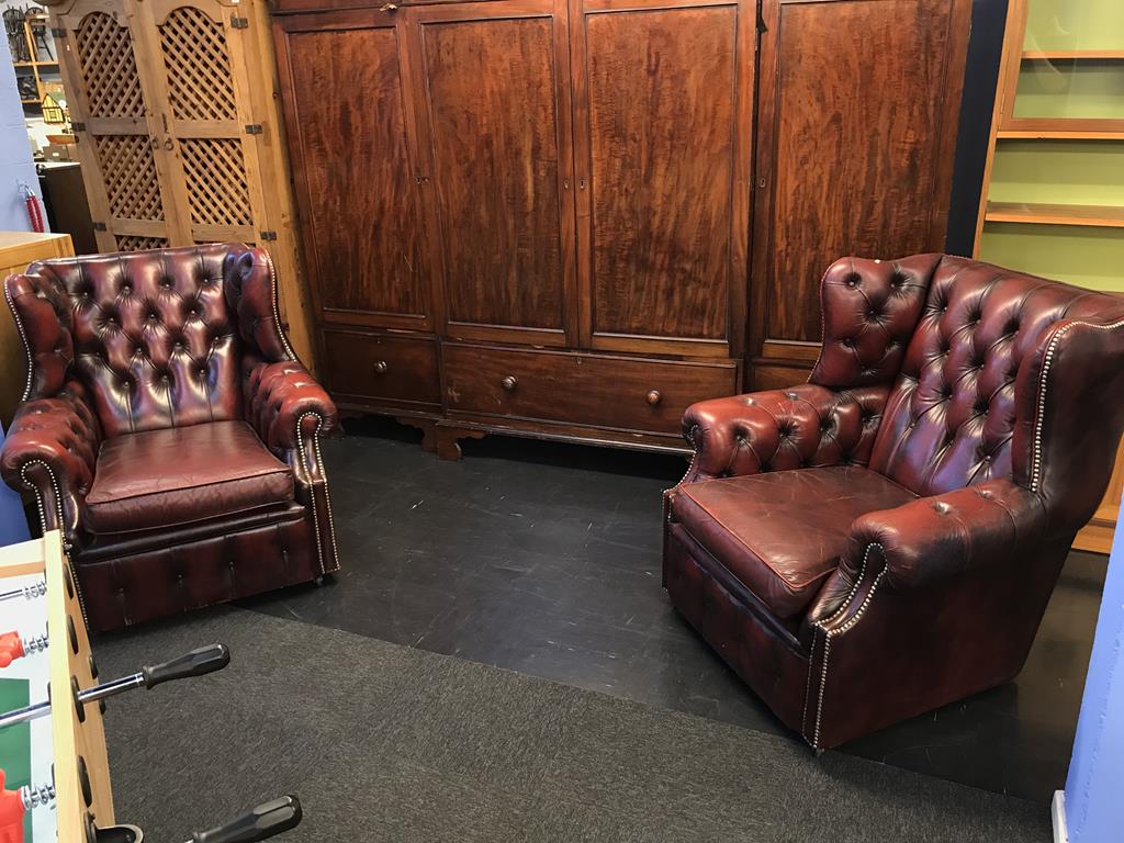 A pair of oxblood Chesterfield armchairs