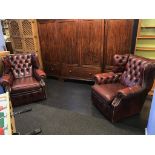 A pair of oxblood Chesterfield armchairs