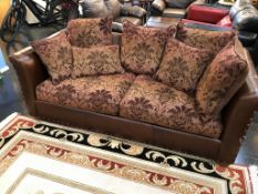 A brown leather settee, with upholstered cushions