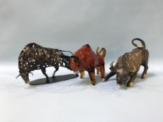 An amber coloured glass model of a bull and two metalwork models of bulls