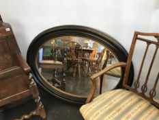 A large ebonised oval mirror