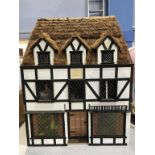 A large thatched black and white cottage Doll's House, 'The Hunting Lodge of Henry VIII', 68cm wide