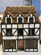 A large thatched black and white cottage Doll's House, 'The Hunting Lodge of Henry VIII', 68cm wide