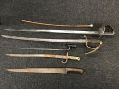 A collection of various swords, bayonets and a swagger stick