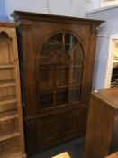 A walnut glazed cabinet with arched door, brushing slide and two cupboard doors, 134cm wide