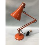 An orange angle poise Lighting Ltd lamp