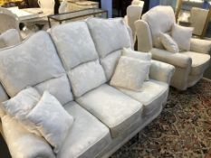 A cream three seater sofa, armchair and pair of wing chairs
