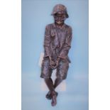 Frederich Goldscheider, a painted terracotta, life size, seated young boy, wearing a cap, hands