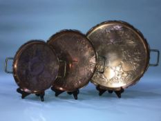 A set of three Edwardian copper and brass graduating circular two handled trays, 43cm diameter (