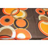 A piece of fabric, the brown ground with overlapping circles in orange, white, brown and black,