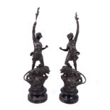 A pair of French Art Nouveau spelter male and female figures holding torches with lions at the base,