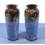 A pair of Doulton stoneware vases, blue with tube lined flowers, signed AT. 26cm tall