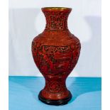 A large Chinese red cinnabar baluster vase with hard wood stand. 50cm tall