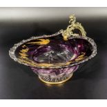 An antique glass bowl with purple and gold decoration containing birds and flowers, the handle is