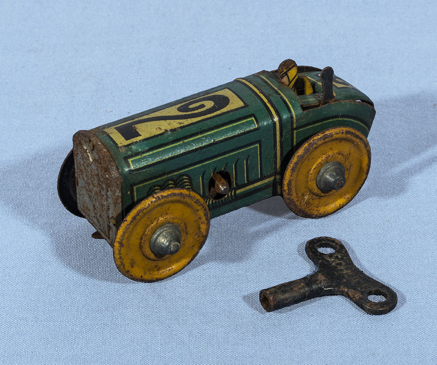 A small tin plate play worn racing car with key in working order. 8cm