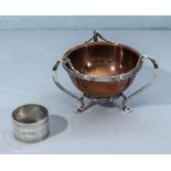 A copper bowl with a silver holder and a silver napkin ring