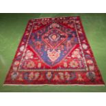 An Oriental red ground wool rug 2m x 1.35m
