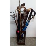 A quantity of walking canes and shooting sticks etc housed in a mahogany stick stand Location: BWR