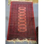 A small Pakistan red ground rug with central line of elephant gulls, multi guard border and