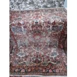A Pakistani red ground rug with images of flora throughout and a multiguard border, 145cm x 205cm