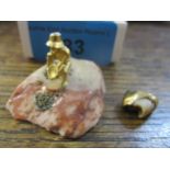 A gold figure of a gold-panner mounted on a gem stone, and a gold tooth crown Location: cab