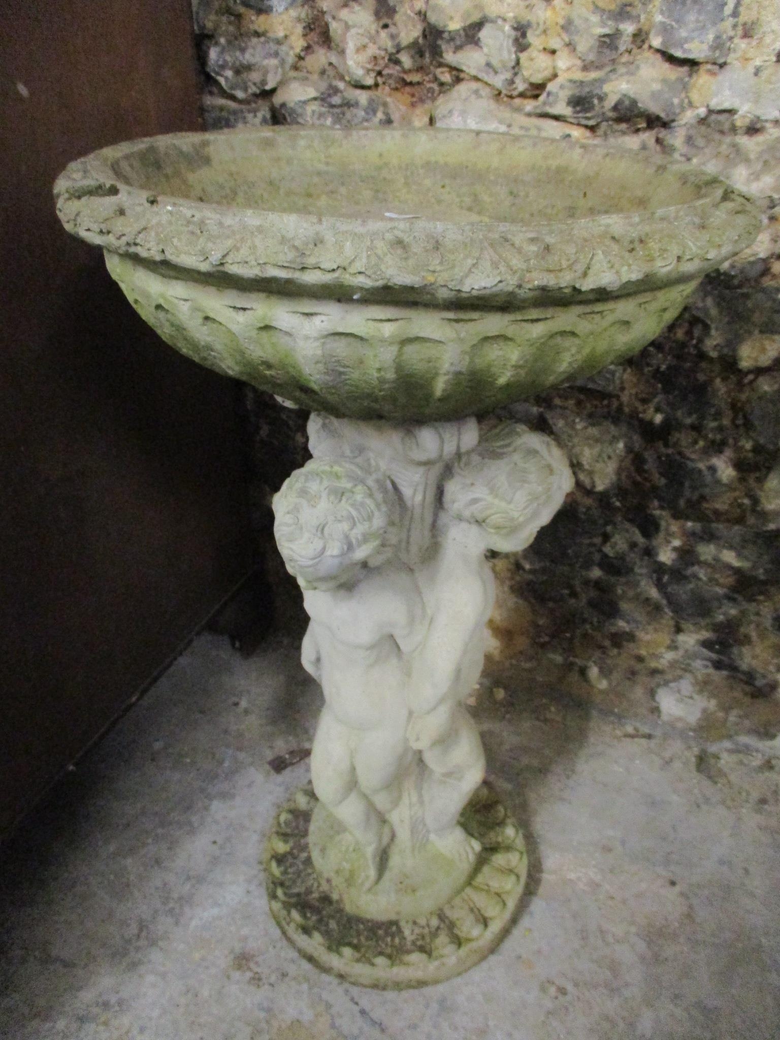 A garden composition bird bath, the column in the form of three cherubs and raised on a circular