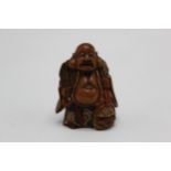 A 19th century Japanese wooden netsuke of Fukurokuju, shoen standing and holding a fan, with red and