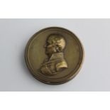 A 19th century brass circular box, the detachable lid embossed with a profile portrait of Duke of