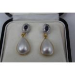 A pair of yellow and white metal earrings each inset with a sapphire cabochon, surrounded by