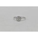 An 18ct white gold diamond ring having a central diamond 4.6mm dia, surrounded by a band of