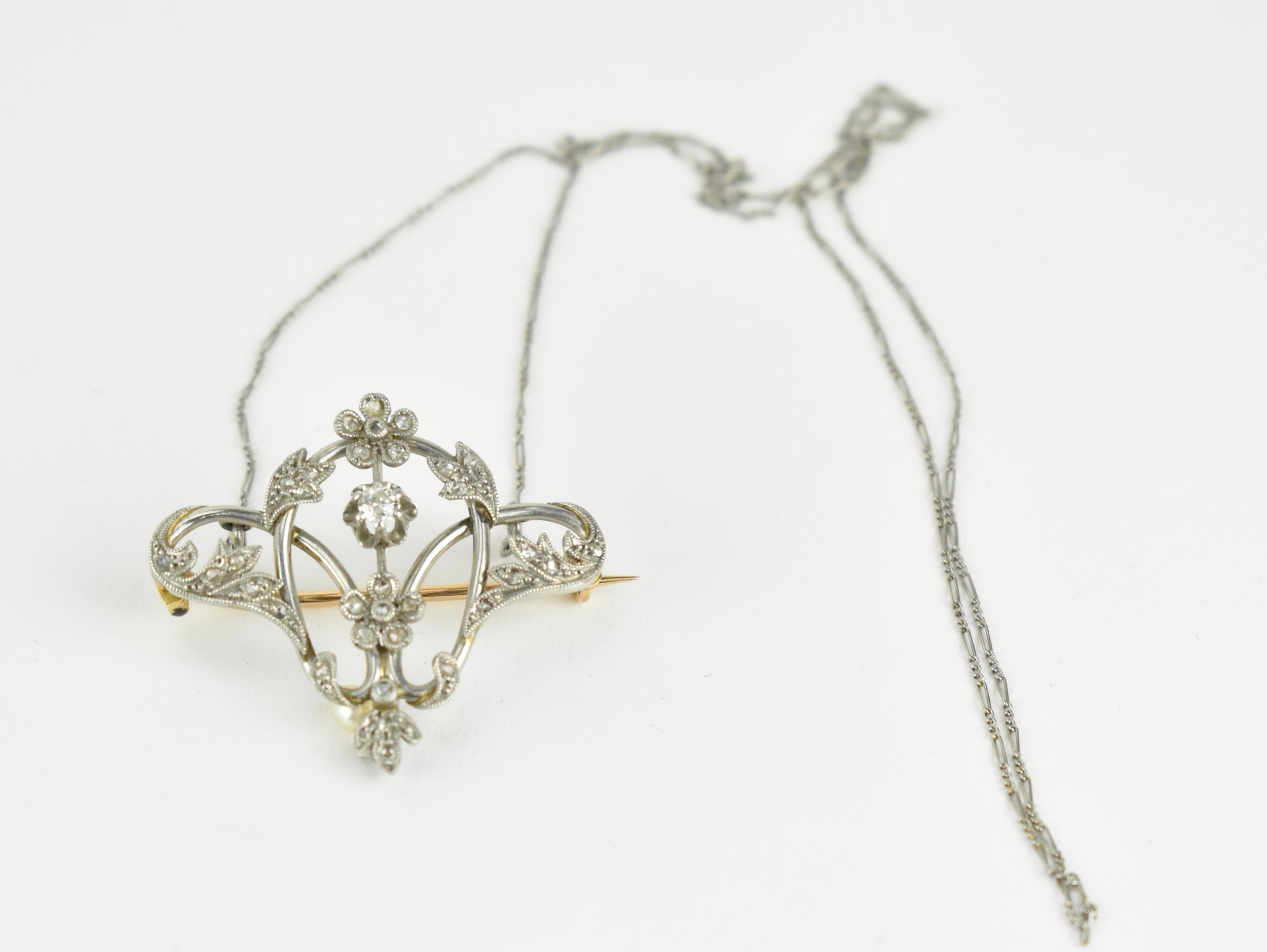 An Art Nouveau white and yellow gold wire framed brooch, fashioned as flowers and scrolled