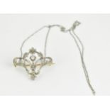 An Art Nouveau white and yellow gold wire framed brooch, fashioned as flowers and scrolled