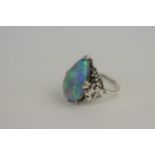 A tear-drop black opal set in white metal, the shoulders decorated in the form of grapevine,