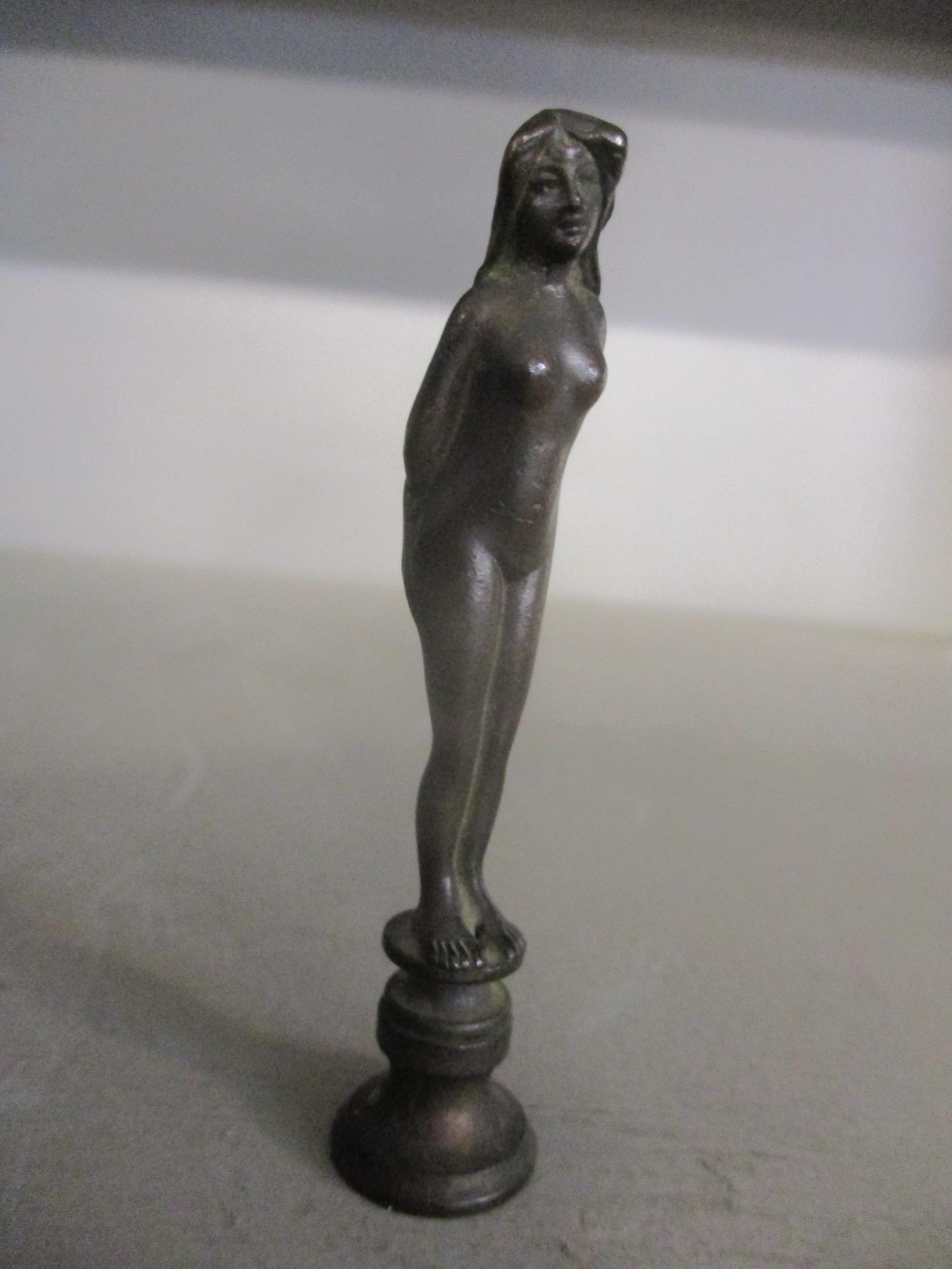 An Art Nouveau patinated bronze desk seal in the form of a standing nude woman, engraved initials to