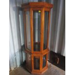 A walnut octagonal shaped display cabinet with loose glass shelves and on a plinth base 186.5cm h