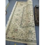 A Persian machine woven beige ground rug with a floral design and tasselled ends, 250cm x 350cm