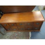 A contemporary hardwood low side chest of spice drawers with patinated brass handles on bracket feet